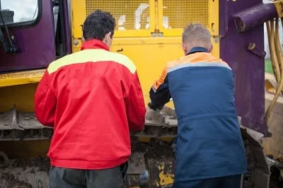 Two contractors working on a piece of machinery.