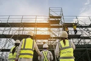 Construction workers on site, wearing yellow safety vests and hardhats.
