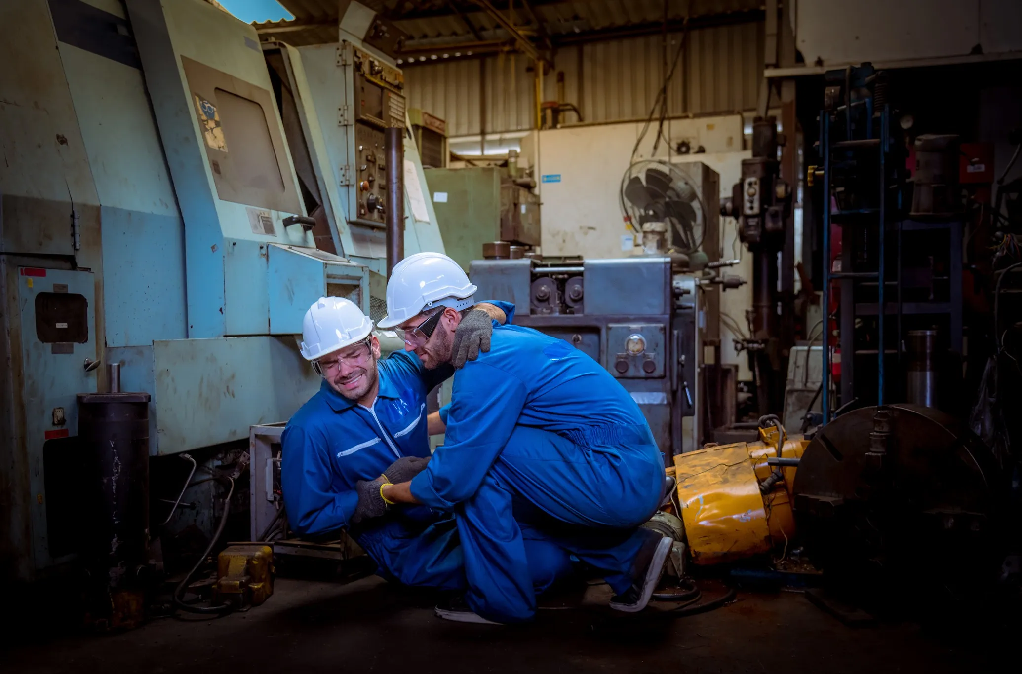 A worker helping an injured worker up from the floor.