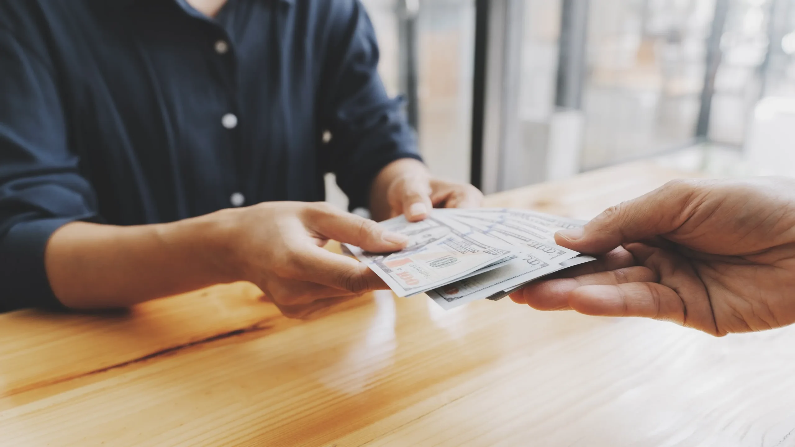 One person handing money to another person.