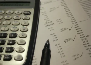 A calculator, pen and receipt on a desk.