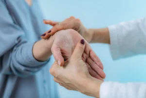 A woman is showing her wrist while a doctor examines it carefully.